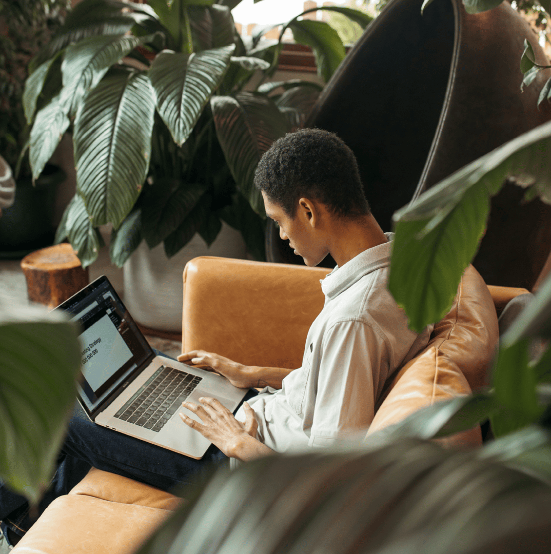 Colleagues collaborating on a laptop while seated in a lounge area with plants