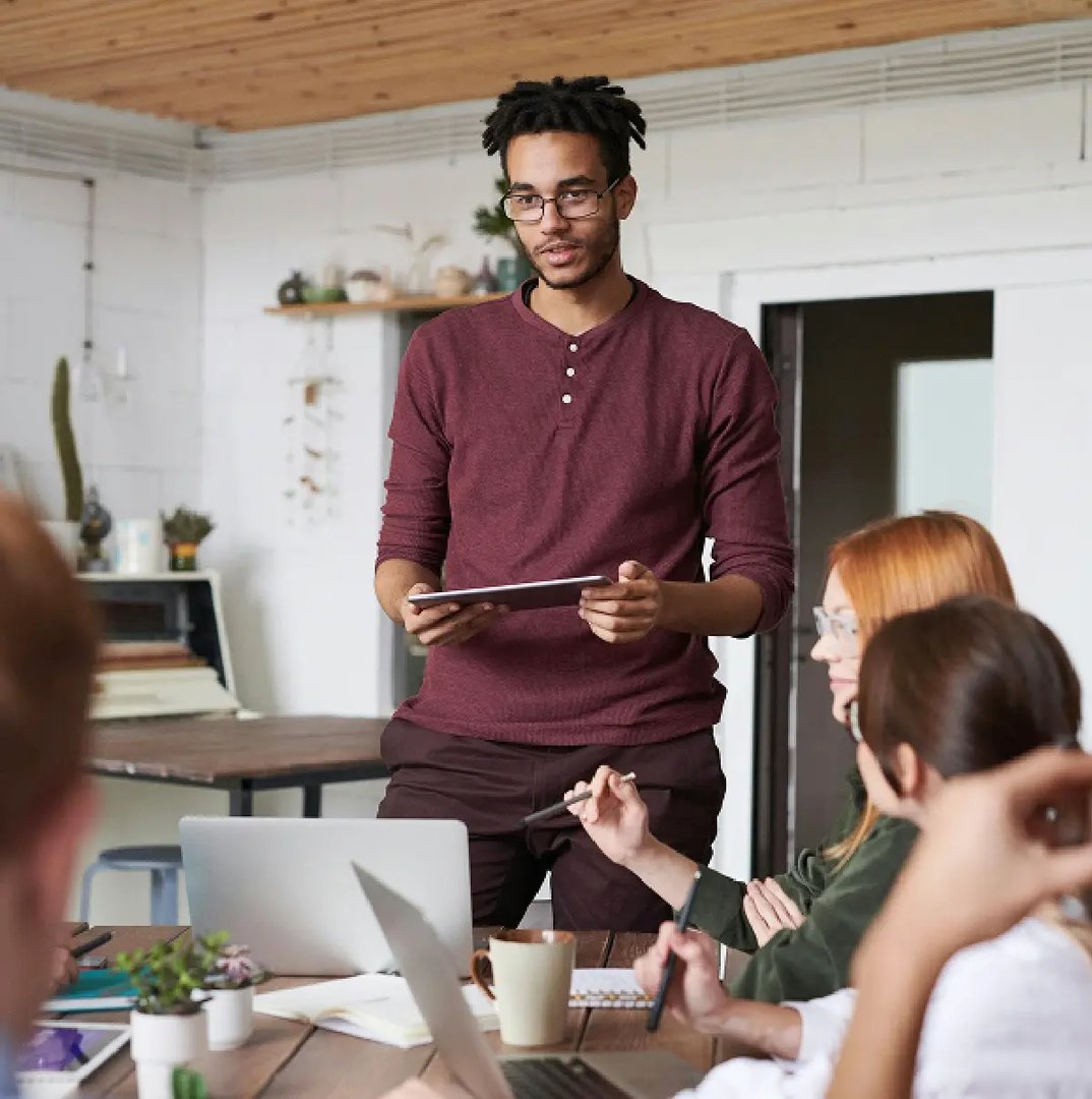Presenter-standing-and-speaking-to-a-small-group-in-a-casual-office-meeting